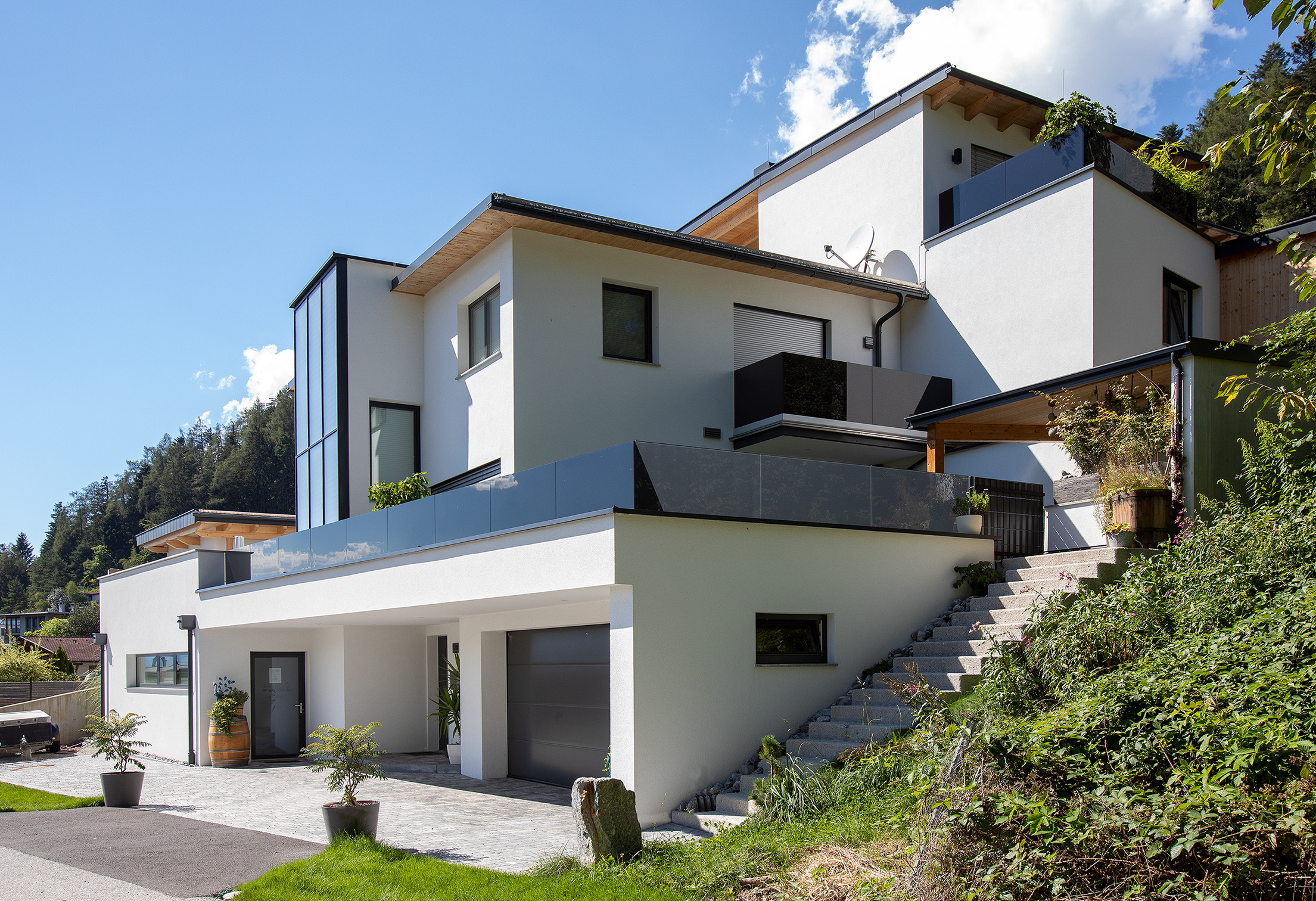 Außenansicht eines Einfamileinhauses im Hang, weiß verputzt