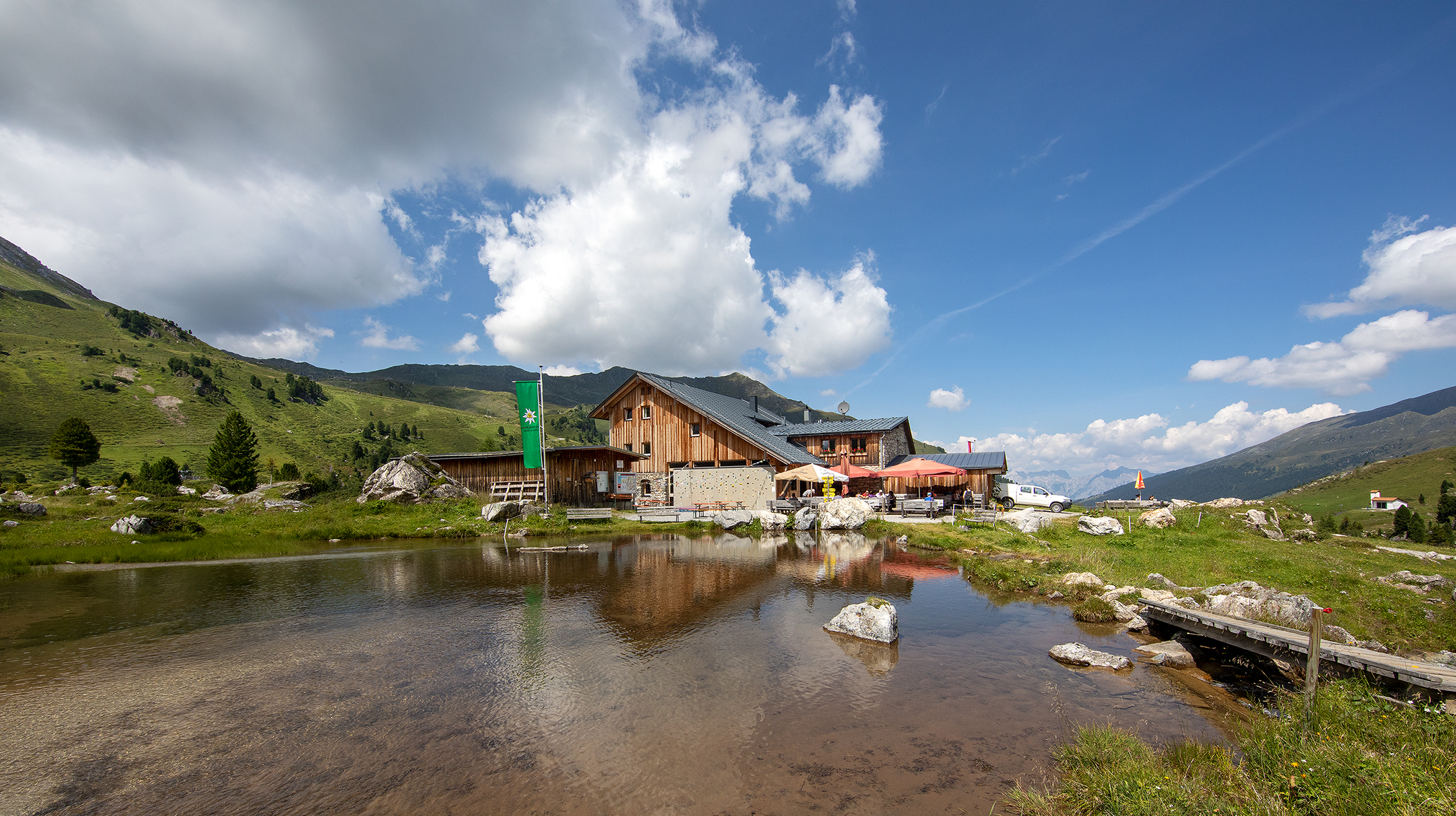 Gesamtansicht der Lizumerhütte mit Teich im Sommer