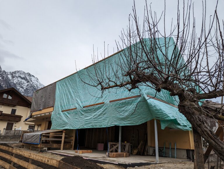 Foto der Doppelhaushälfte im Bau, mit Gewebeplane verpackt